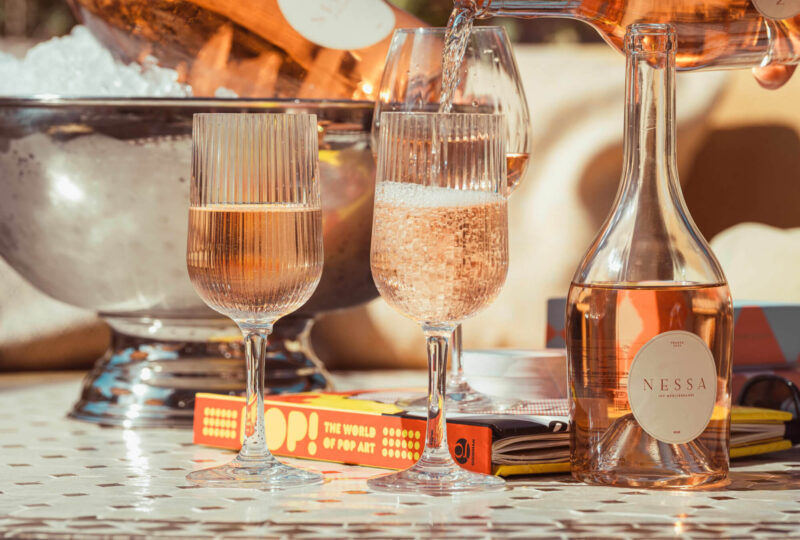 Vino rosado servido en copas Stripe de 30 cl, hechas de plástico irrompible, sobre una mesa en un entorno soleado al aire libre con un ambiente refinado.